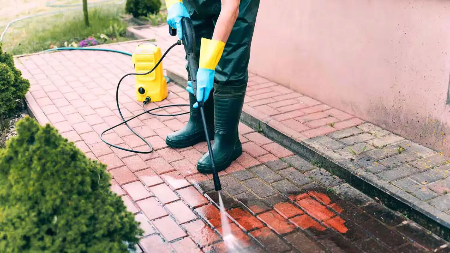 Photo of man pressure washing brick walkway